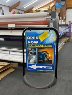 Double-sided outdoor pavement sign for car wash advertising, featuring a durable weather-resistant frame designed by Atlantic Design, used to display promotional messages and offers.
